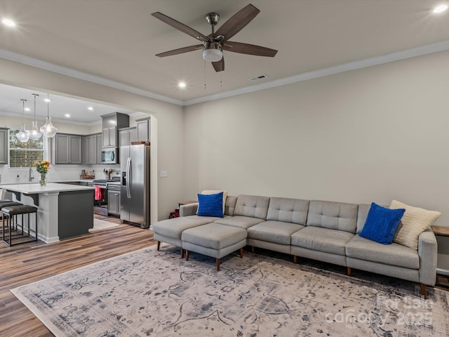 living room with hardwood / wood-style flooring, ceiling fan, and crown molding