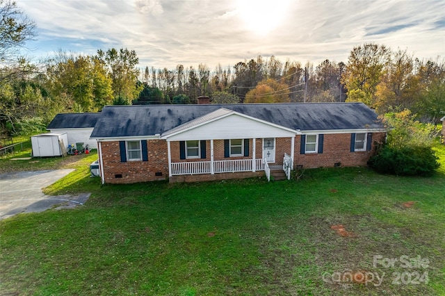 ranch-style home with covered porch, a shed, and a yard