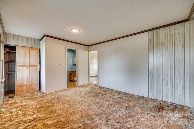 unfurnished bedroom with light carpet, ensuite bathroom, ornamental molding, a textured ceiling, and a closet