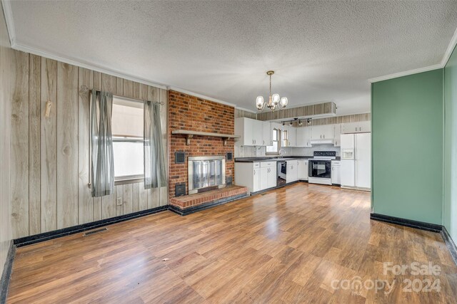 kitchen with wood walls, decorative light fixtures, white appliances, and light wood-type flooring