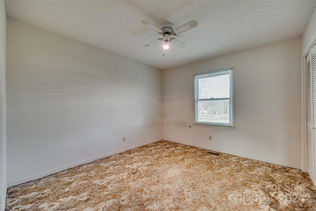 empty room featuring carpet flooring, ceiling fan, and a textured ceiling