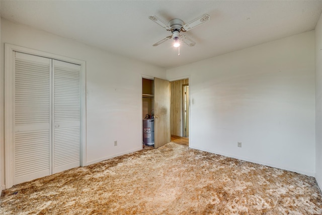 unfurnished bedroom featuring carpet flooring, ceiling fan, a closet, and water heater