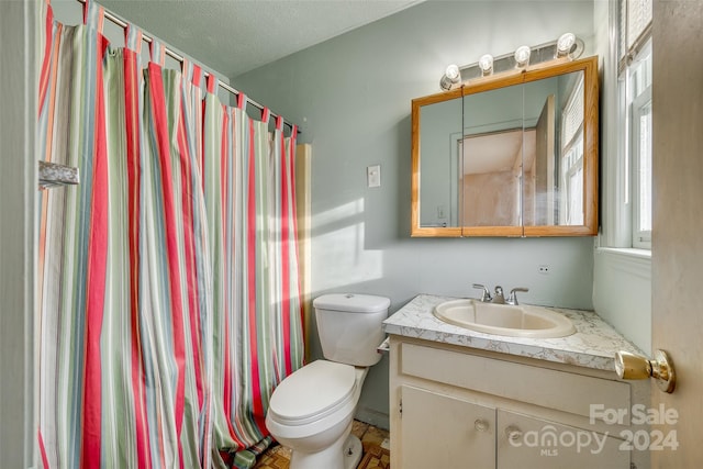 bathroom with a textured ceiling, vanity, toilet, and walk in shower