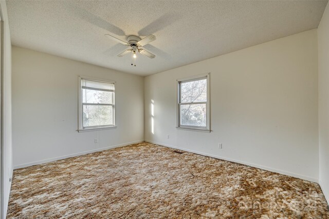 carpeted spare room featuring plenty of natural light, ceiling fan, and a textured ceiling