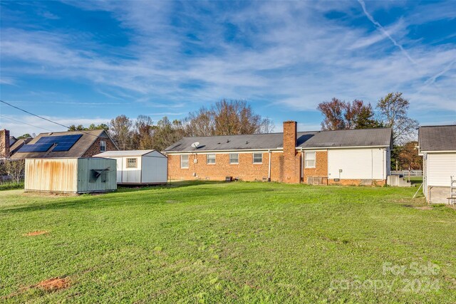 rear view of property with a yard and a storage shed