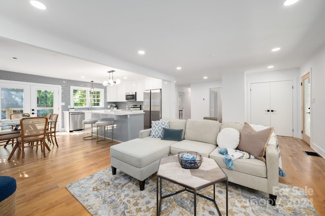 living room with a chandelier, french doors, and light hardwood / wood-style floors