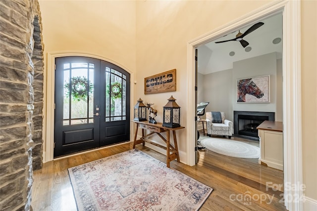 entryway with a stone fireplace, french doors, and hardwood / wood-style flooring