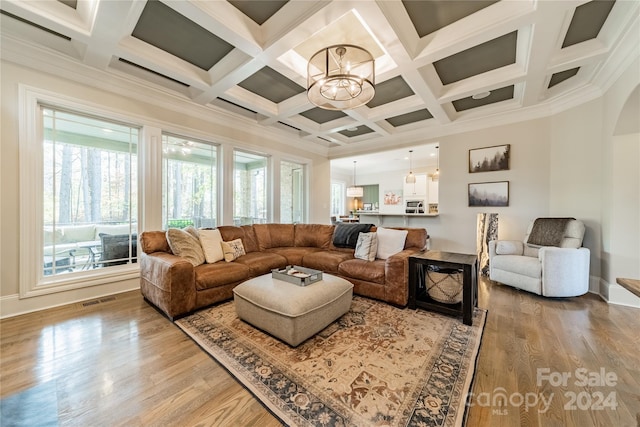 living room featuring crown molding, beam ceiling, coffered ceiling, hardwood / wood-style flooring, and a chandelier