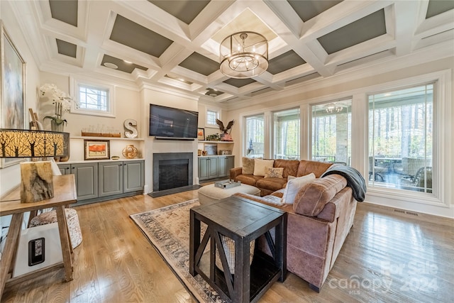 living room featuring light wood-type flooring, coffered ceiling, a healthy amount of sunlight, and beamed ceiling