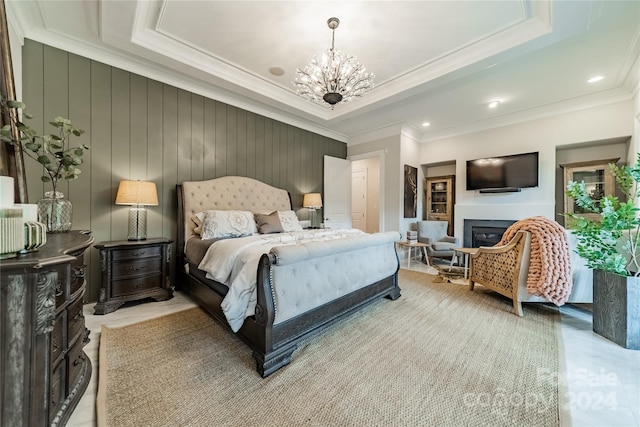 bedroom featuring ornamental molding, wooden walls, a chandelier, and a raised ceiling