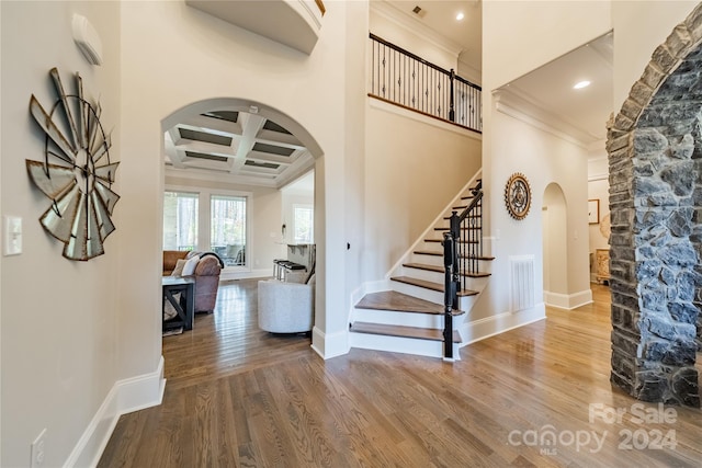 staircase featuring hardwood / wood-style flooring, a high ceiling, and coffered ceiling