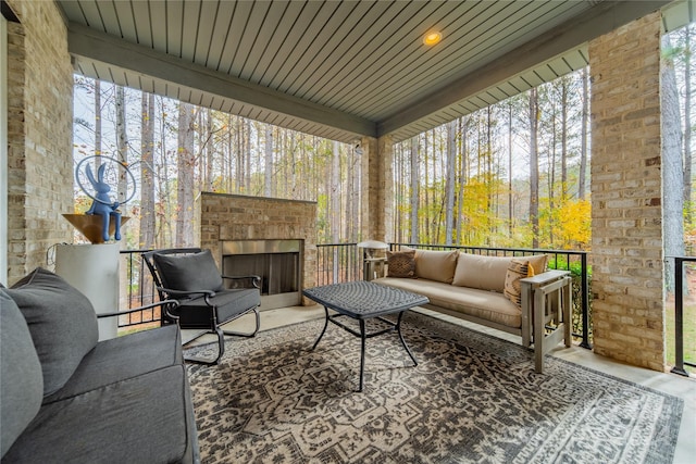 sunroom featuring an outdoor brick fireplace and wood ceiling