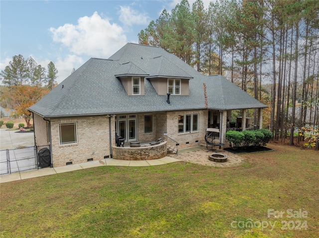 back of property with a patio, a lawn, and an outdoor fire pit