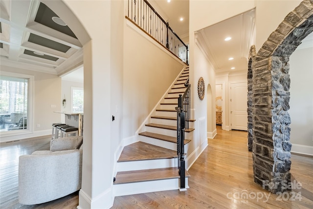 stairway with ornamental molding, hardwood / wood-style floors, beamed ceiling, and coffered ceiling