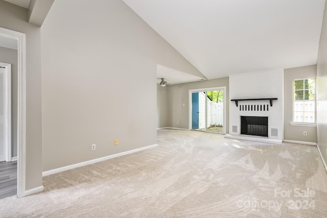 unfurnished living room with high vaulted ceiling, light carpet, and a fireplace