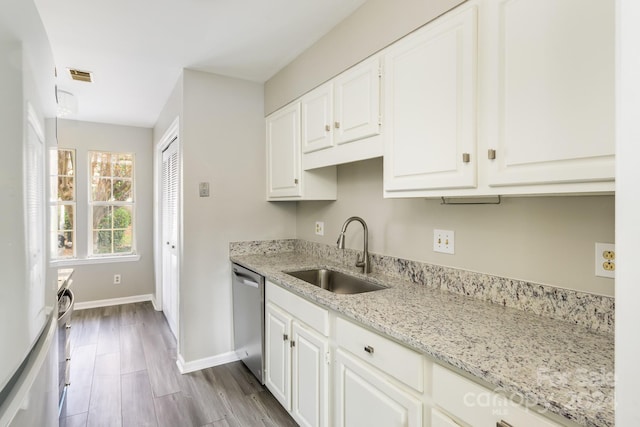 kitchen with light hardwood / wood-style floors, dishwasher, white cabinets, sink, and light stone countertops