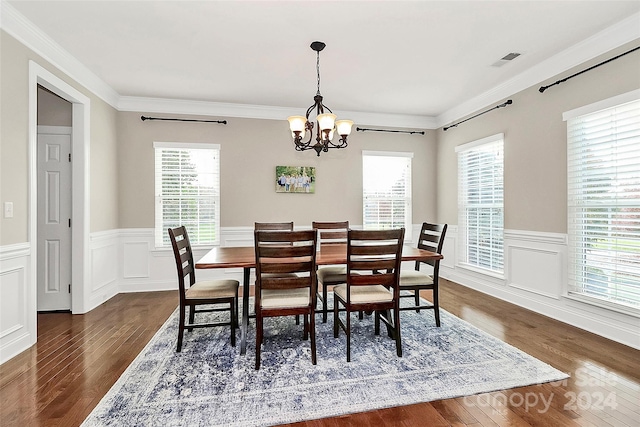 dining space featuring dark wood-type flooring, crown molding, and a notable chandelier