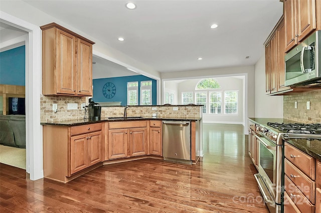 16404 Grassy Creek Dr, Huntersville, NC 28078 - kitchen with appliances with stainless steel finishes, decorative backsplash, dark wood-style flooring, dark stone counters, and a peninsula