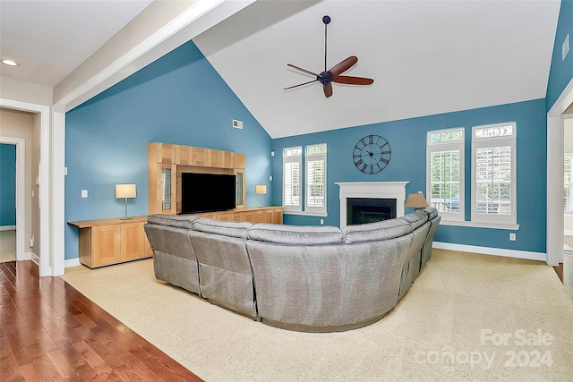 living room with hardwood / wood-style floors, ceiling fan, and high vaulted ceiling