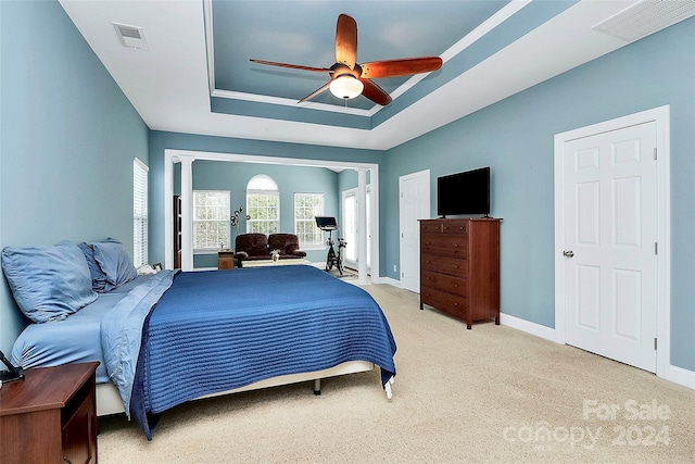 carpeted bedroom featuring ceiling fan and a tray ceiling