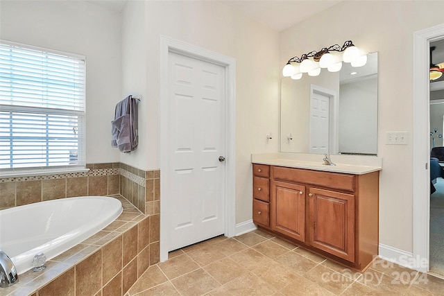 bathroom featuring tile patterned flooring, vanity, and tiled tub