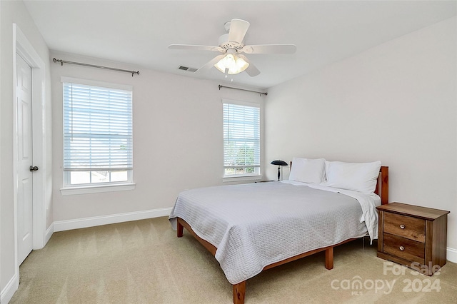 carpeted bedroom featuring multiple windows and ceiling fan