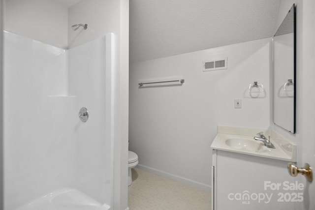 bathroom with toilet, a textured ceiling, walk in shower, tile patterned flooring, and vanity