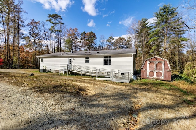 rear view of house featuring central AC and a shed