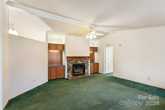 unfurnished living room with a stone fireplace, ceiling fan, dark colored carpet, and vaulted ceiling with beams