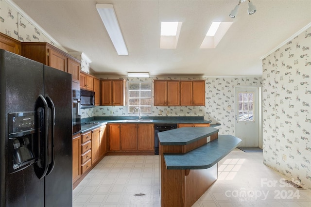 kitchen featuring a wealth of natural light, a skylight, black appliances, and crown molding