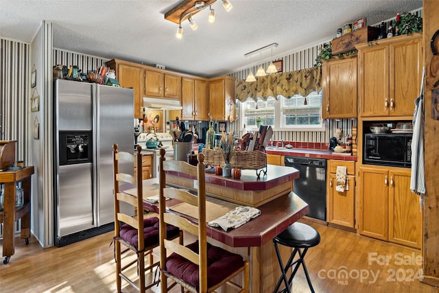 kitchen with light hardwood / wood-style floors, black appliances, ornamental molding, a textured ceiling, and pendant lighting