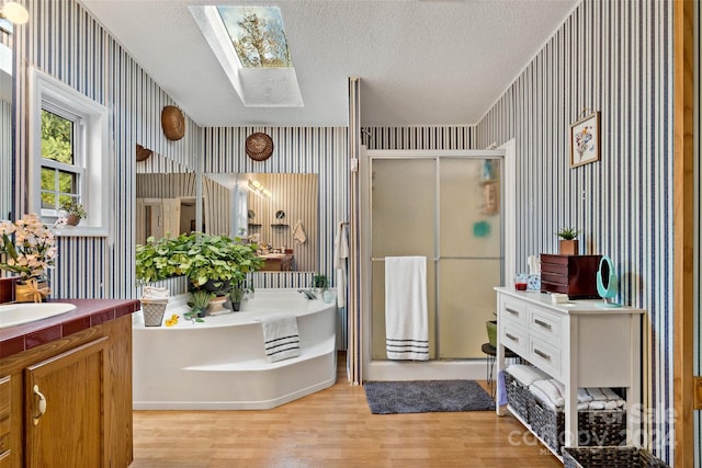 bathroom with hardwood / wood-style flooring, a textured ceiling, a skylight, independent shower and bath, and vanity