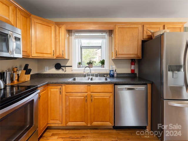 kitchen featuring stainless steel appliances, sink, and light hardwood / wood-style flooring