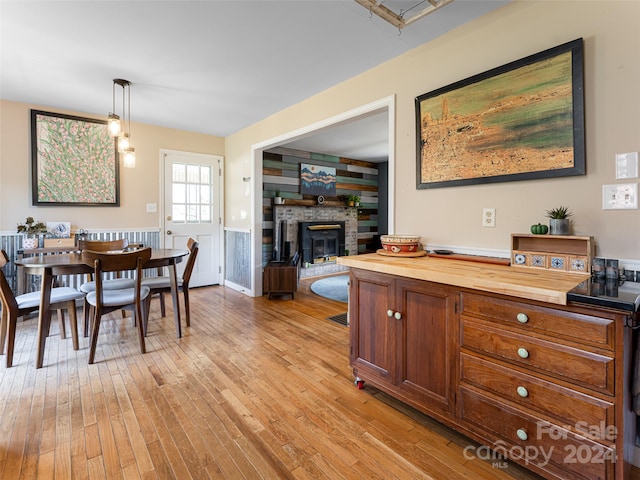 dining room with wood walls, light hardwood / wood-style floors, and a stone fireplace