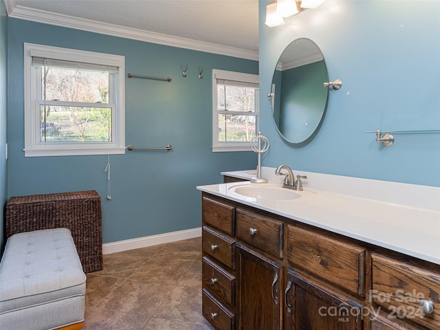 bathroom with a wealth of natural light, vanity, a textured ceiling, and ornamental molding