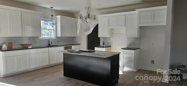 kitchen featuring white cabinets, decorative backsplash, a kitchen island, and sink