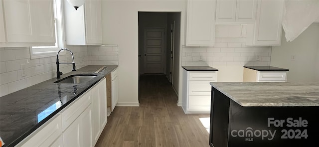 kitchen featuring decorative backsplash, light wood-type flooring, dark stone counters, sink, and white cabinetry