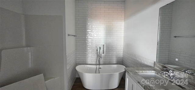 bathroom featuring a bathing tub, vanity, and tile walls