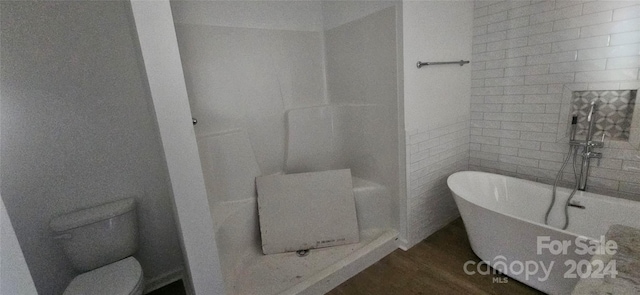 bathroom featuring a washtub, hardwood / wood-style floors, and toilet