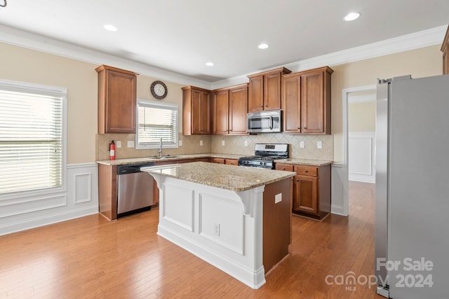 kitchen featuring hardwood / wood-style floors, a kitchen island, ornamental molding, and appliances with stainless steel finishes