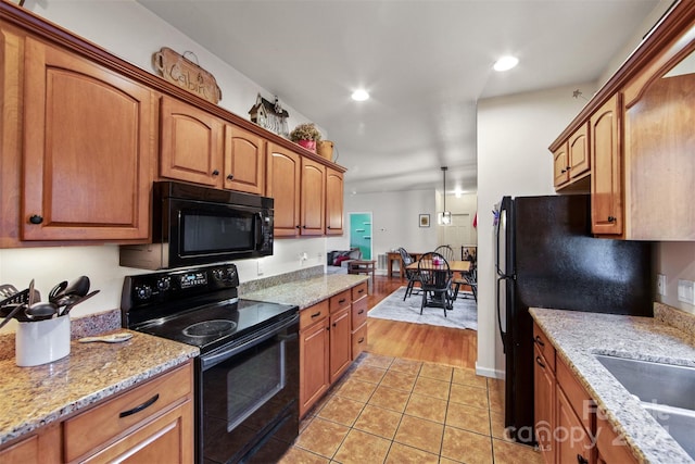 688 Olympic Dr Unit 2, Whittier, NC 28789 - kitchen with black appliances, light tile patterned flooring, light stone countertops, brown cabinets, and recessed lighting