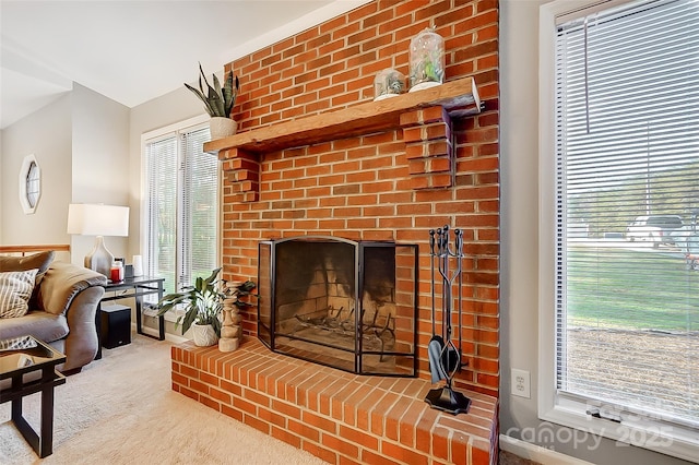 living room with lofted ceiling, a brick fireplace, and carpet floors