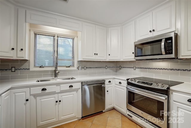 kitchen featuring stainless steel appliances, light tile patterned floors, decorative backsplash, white cabinets, and sink