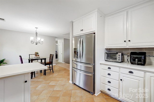 kitchen with white cabinets, decorative light fixtures, light tile patterned floors, stainless steel refrigerator with ice dispenser, and a chandelier