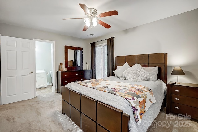 bedroom with ceiling fan, ensuite bathroom, and light carpet