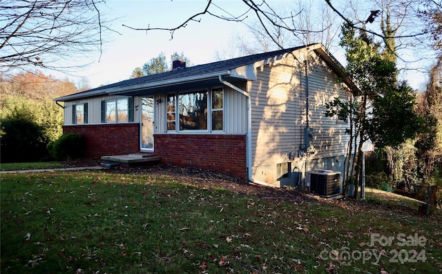 view of front facade with a front lawn and central air condition unit