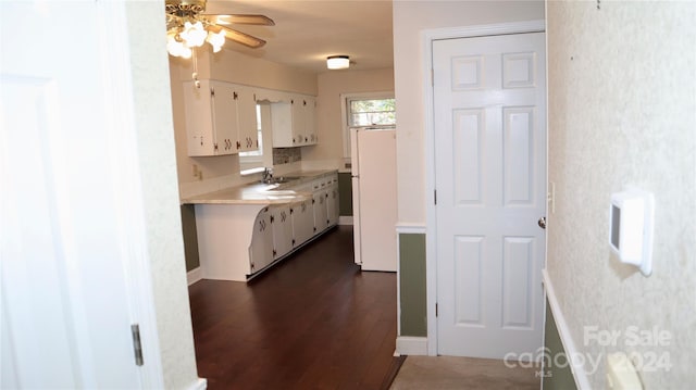 kitchen with ceiling fan, sink, dark hardwood / wood-style flooring, white fridge, and white cabinets