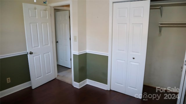 unfurnished bedroom featuring a closet and dark wood-type flooring