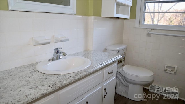 bathroom featuring vanity, toilet, wood-type flooring, and tile walls