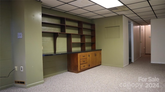 basement with a drop ceiling and light colored carpet